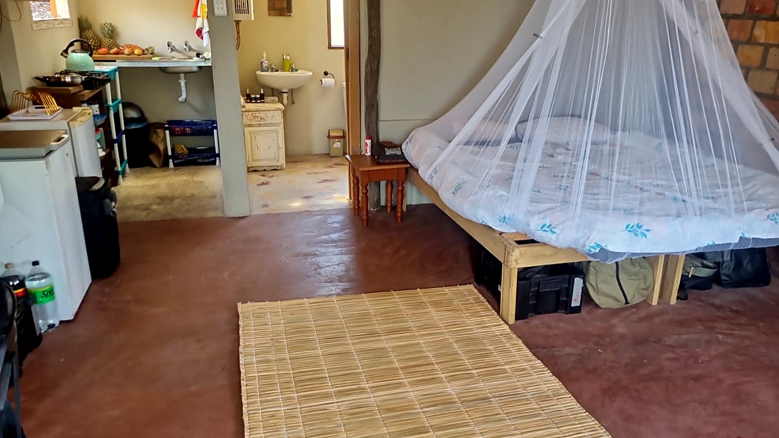 The open-plan room in the Cottage, with a bed under a mosquito net and a kitchenette